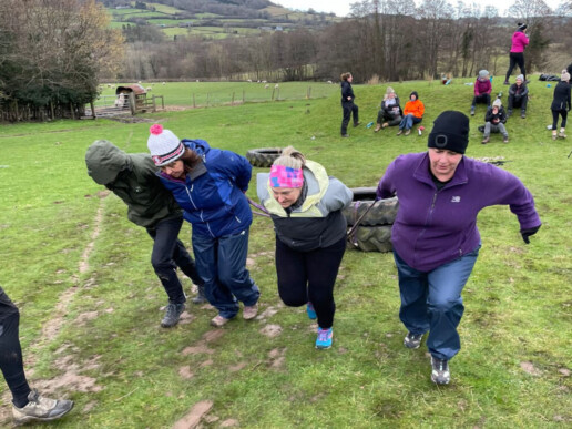 Four colleagues pulling a tractor tire