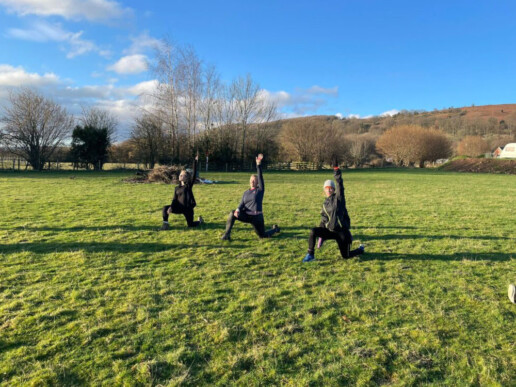 Three colleagues doing stretches on a hillside